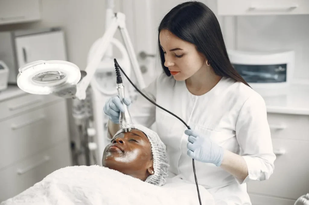 A woman lying in a treatment room receiving treatment to her forehead