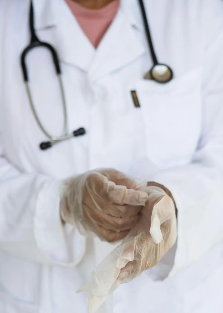 A doctor with a white coat on putting on gloves